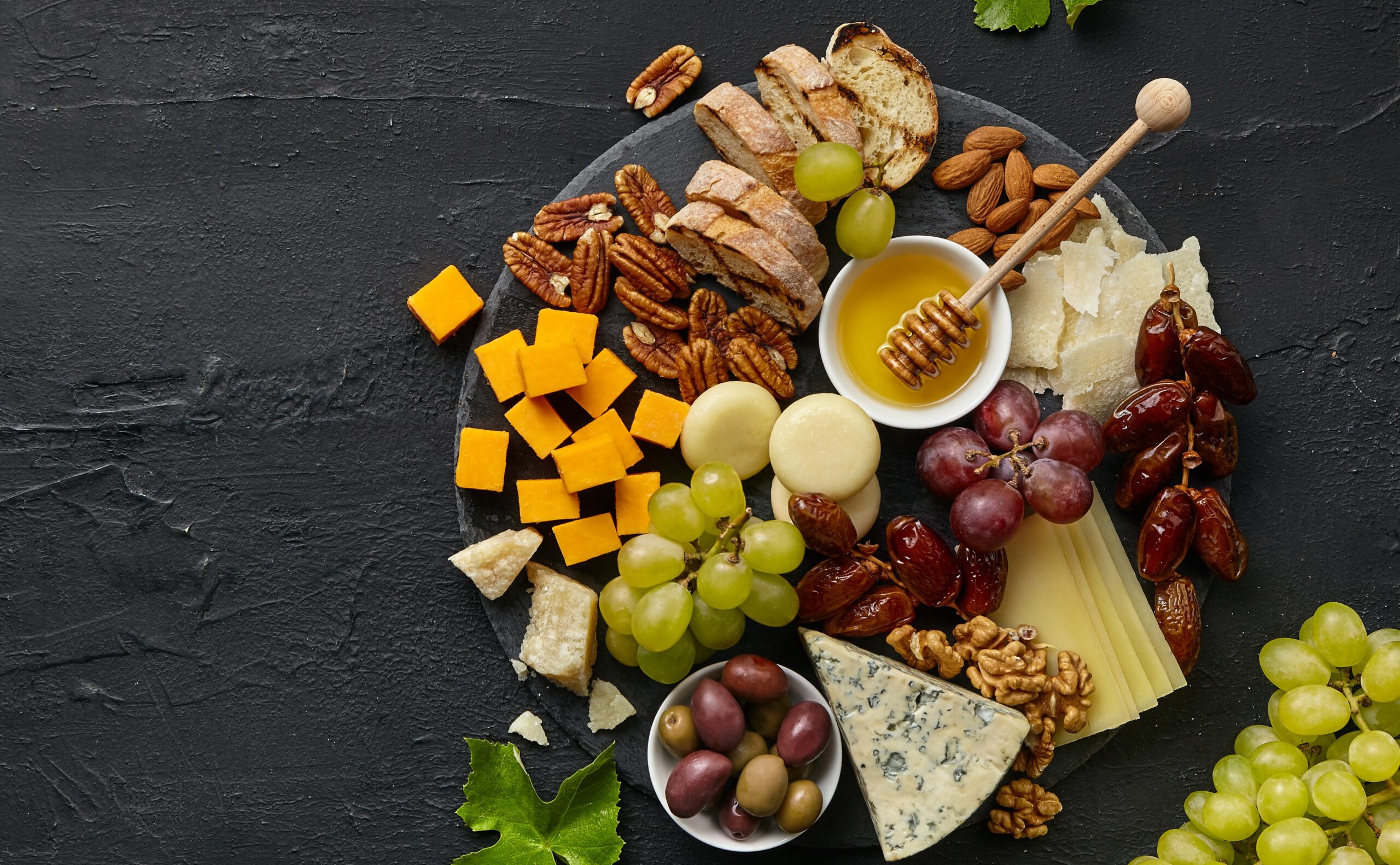 top-view-of-tasty-cheese-plate-with-fruit-on-the-black-stone